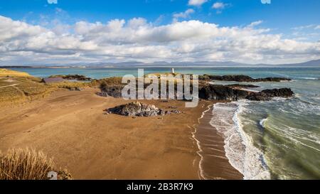 Ein Blick auf Twr Bach und die schneebedeckten Snowdonia Berge über Porth Twr Mawr auf Llanddwyn Island, Anglesey Stockfoto