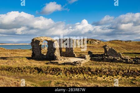 Das keltische Kreuz betrachtete die Ruinen der St. Dwynwen-Kirche auf der Insel Llanddwyn, Anglesey, Nordwales Stockfoto