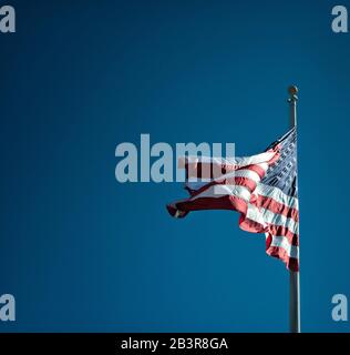 US-Sterne und Streifen fahnen im Wind vor blauem Himmelshintergrund. Stockfoto