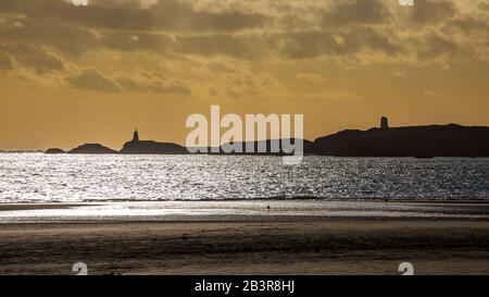 Eine Silhouette der Insel Llanddwyn und der Leuchttürme von Twy Bach und Twr Mawr vom Strand von Newborough, Anglesey Stockfoto
