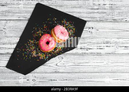 Mehrere frische Donuts in einem schwarzen Keramikplatte auf einem Holztisch mit Kopie Raum Stockfoto