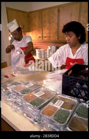 Austin, Texas, USA, um 1989: Die Freiwilligen von Meals on Wheels packen zubereitete Lebensmittel für die Lieferung an einkommensschwache Einwohner von Austin ein. ©Bob Daemmrich Stockfoto