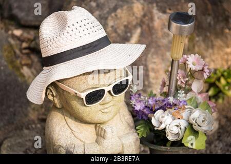 Zeitgenössische buddha-statue mit Hut und Sonnenbrille, die auf dem Spaziergang auf dem Berg Mischen, in der Nähe von Kiezu-no-Hi (Die ewige Flamme) auf der Miyajima-Insel, Japan, zu sehen ist Stockfoto