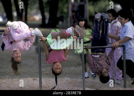 Austin Texas USA: Studenten hängen kopfüber an Metallstangen während der Aussparung auf dem Spielplatz der Grundschule. ©Bob Daemmrich Stockfoto