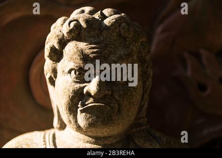 Wildes, unfreundliches Gesicht der Steinstatue, zu sehen auf dem Spaziergang auf dem Berg Misen in der Nähe des Kiezu-no-Hi (Die ewige Flamme) auf Miyajima-Insel, Japan Stockfoto