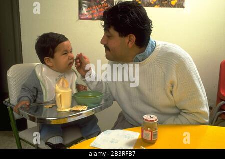 Austin, Texas, USA, um 1988: Der hispanische Vater ernährt seinen 18 Monate alten Kleinkind. ©Bob Daemmrich Stockfoto