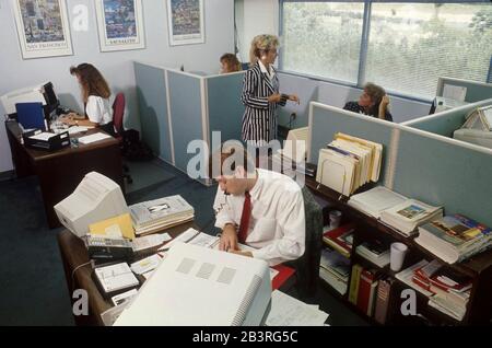 Austin, Texas, USA, um 1992: Mitarbeiter in Großraumbüros und offenen Etagen arbeiten an Komutern in einem geschäftigen Reisebüro. ©Bob Daemmrich Stockfoto