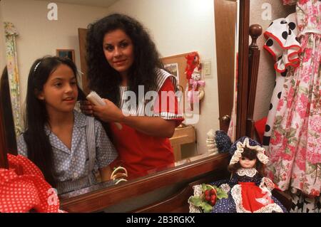 Austin Texas USA, um 1992: Hispanische Mutter hilft Tochter sich anzuziehen. ©Bob Daemmrich Stockfoto