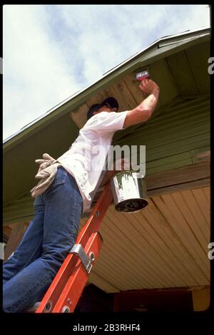 Midland, Texas, USA, 1989: Ehrenamtliche Bemalung von Dachrinnen von einkommensschwachen Häusern während des „Weihnachts im April“-Tages, der von Kirchen in der Region gesponsert wird. ©Bob Daemmrich Stockfoto