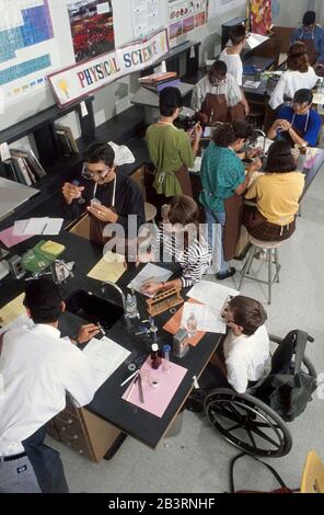 Austin, Texas, USA, um 1997: Behinderter Junge im Rollstuhl nimmt an Laborexperimenten mit Klassenkameraden während des Biologieklasseniveaus der High School Teil. ©Bob Daemmrich Stockfoto