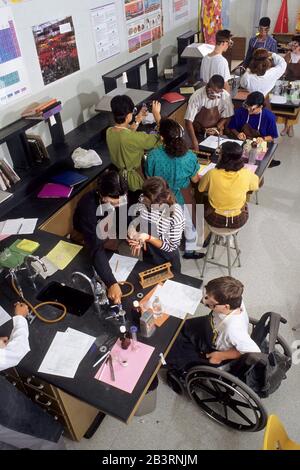 Austin, Texas, USA, um 1997: Behinderter Junge im Rollstuhl nimmt an Laborexperimenten mit Klassenkameraden während des Biologieklasseniveaus der High School Teil. ©Bob Daemmrich Stockfoto