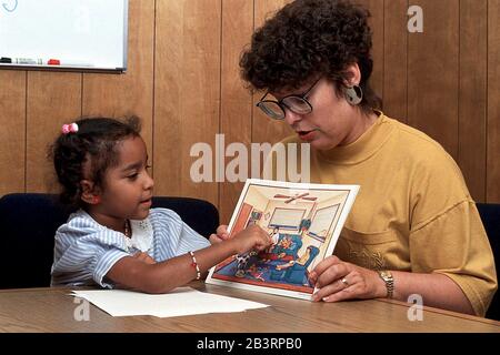 Austin Texas USA, um 1991: Der Sprachtherapeut einer öffentlichen Schule nutzt Bildband, um Antworten des 6-jährigen Hispanic während einer Einzeltherapie zu erhalten. ©Bob Daemmrich Stockfoto