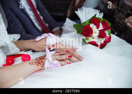 Hochzeitstag. Die Frau hat handgefertigte Henna und Handtuch. Roter Hochzeitsbouquet. Die Frau hielt die Frau im Auto. Stockfoto