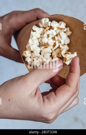 Frau, die einen Papierkegel voller Popcorn hält. Draufsicht. Ansicht von oben Stockfoto