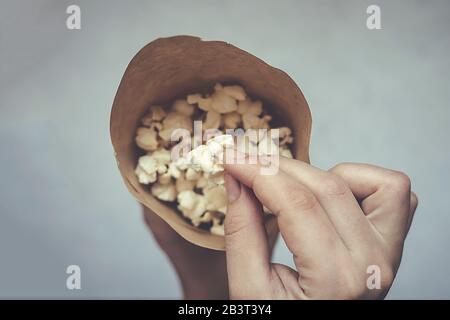 Frau, die einen Papierkegel voller Popcorn hält. Draufsicht. Ansicht von oben Stockfoto