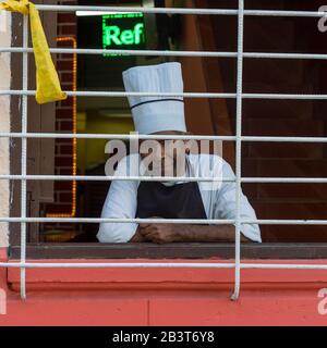 Porträt des männlichen Chefkochs, der durch Fenster blickt, Havanna, Kuba Stockfoto