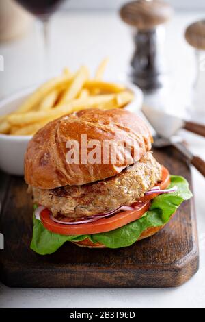 Veganer Burger auf Pflanzenbbasis mit Tomaten und Salat, serviert mit Pommes Frites Stockfoto