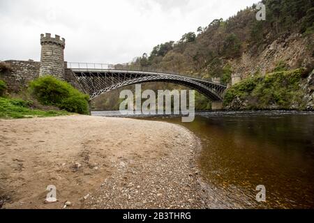 Bank of the River Spey mit der Craigellachie-Brücke aus Gusseisen im Hintergrund Stockfoto