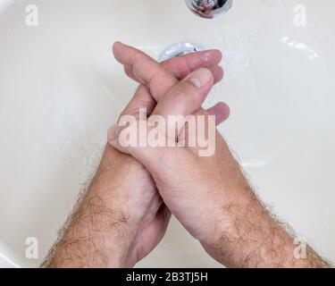 Mann, der die Hände aus der Nähe von oben waschen kann, einer von mehreren Handwaschschritten für eine gründliche Reinigung Stockfoto