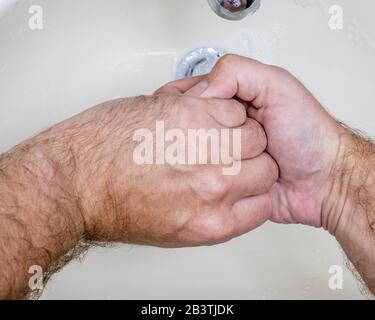 Mann, der die Hände aus der Nähe von oben waschen kann, einer von mehreren Handwaschschritten für eine gründliche Reinigung Stockfoto