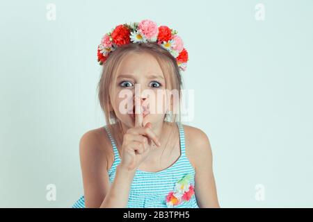 Porträt einer schönen Frau mit Finger auf den Lippen, Gesting Hush, Keep Silence, es ist ein Geheimnis. Nahaufnahme des kaukasischen Kindermodells mit geblümtem Stirnband iso Stockfoto