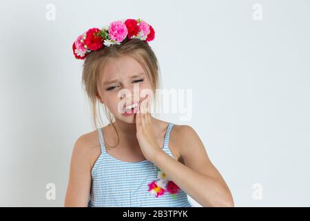 Closeup Portrait Girl, Kind mit empfindlichem Zahnschmerzen Krone Problem, von Schmerzen zu weinen, die mit der Hand isoliert hellblau grau BA den Mund berühren Stockfoto