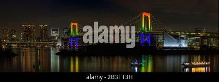 Ein Panoramabild der beleuchteten Rainbow Bridge in der Tokioter Bucht, nachts (Tokio). Stockfoto