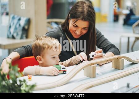 Süßes Kleinkind mit Mutter spielt mit Autotoys im Spielzimmer im Einkaufszentrum Stockfoto