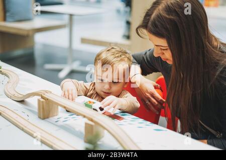 Süßes Kleinkind mit Mutter spielt mit Spielzeug im Spielzimmer im Einkaufszentrum Stockfoto