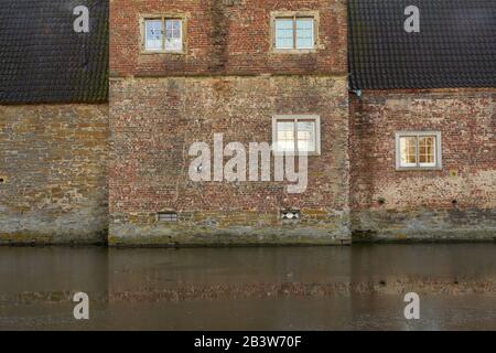 Alte Ziegelsteinhausfassade mit kleinen Fenstern Stockfoto
