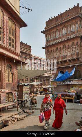 Frauen in bunten Saris schlendern durch die Straßen von Bikaner mit typischen Havelis, Rajasthan, Indien Stockfoto