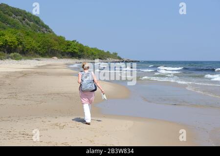 Eine Frau, die an einem sandigen Strand, Skane, Schweden, spazieren geht Stockfoto