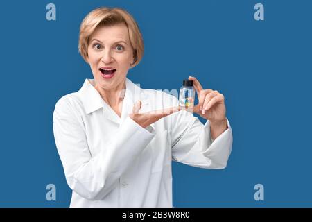 Doktor der mittleren Frau, der auf Pillen im Glasbehälter zeigt Stockfoto