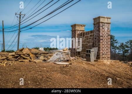 Baustelle einer neuen Gemeindemauer, die auf einem Hügel mit Backstein- und Steinblick mit Stromleitungen über dem Kopf an einem sonnigen Tag installiert wird Stockfoto