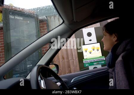 Frau, die auf Drive Thru Menu und McDonalds blickt. England Stockfoto
