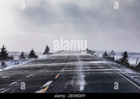 Route 10 Highway mit Schneeverwehung über die Straße an einem stürmischen Wintertag auf der Avalon Peninsula, Neufundland, Kanada Stockfoto
