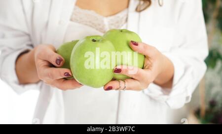 Nahaufnahme der weiblichen Hände mit drei grünen Äpfeln Stockfoto