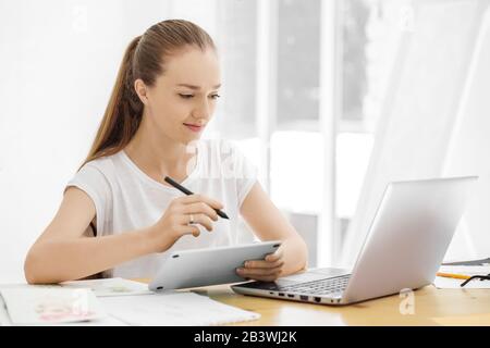 Grafikdesigner zieht auf ein Tablet zurück. Das Konzept von kreativer Arbeit, Studium, Hobby und Freiberufler. Stockfoto