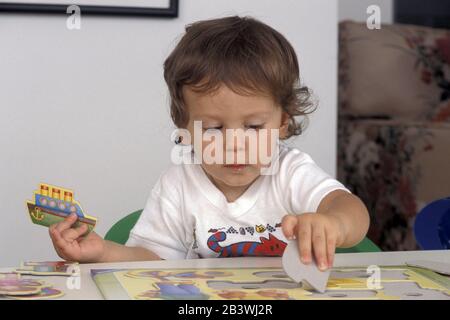 Austin, Texas USA, 1995: Kleinkind passt Formen mit leeren Räumen auf einem Puzzletafel an. ©Bob Daemmrich Stockfoto