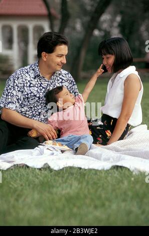 Austin, Texas, USA, 1995: Hispanischer Vater und philippinisch-amerikanische Mutter mit zweijähriger Tochter spielen im Park. HERR ©Bob Daemmrich Stockfoto