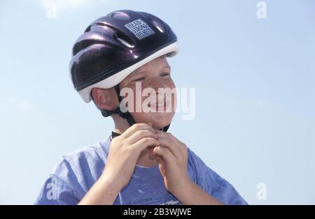 Austin, Texas USA: Der 13-jährige Junge setzt sich vor dem Mountainbiken richtig einen Schutzhelm an. HERR ©Bob Daemmrich Stockfoto