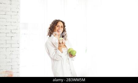 Senior Happy Woman mit lockigen Haaren mit grünen Äpfeln. Ernährung. Gesunder Lebensstil. Stockfoto