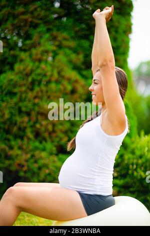 Schwangere Frau Streckt Die Hände, Während Sie Auf Dem Yoga-Ball Sitzt Stockfoto