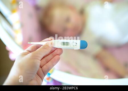 Nahmedizinisches Thermometer, Eltern messen die Temperatur des kranken Kindes, 1 Jahre altes Kleinkind, das hohes Fieber im Bett liegt. Fieber im Kind. Stockfoto