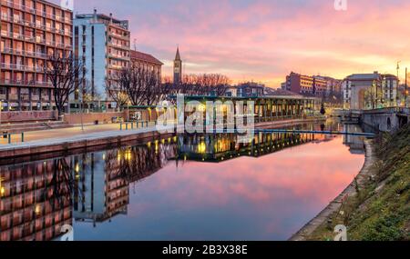 Mailand, Italien - 10. Februar 2020: Porta Ticinese Quarter in der Mailänder Innenstadt, das im Darsena del Naviglio Kanal bei dramatischem Sonnenaufgang reflektiert. Diese Stadt a Stockfoto