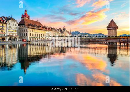 Historische Holzkapellenbrücke und Altstadt von Luzern, Schweiz, reflektieren im Fluss Reuss über drastischen Sonnenaufgang Stockfoto