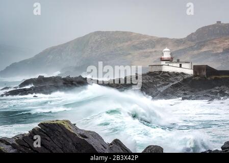 Stürmische Meere und hohe Wellen, die auf den Felsen vor dem Leuchtturm von Valentia im County Kerry Ireland abstürzen Stockfoto