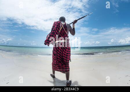 Kenianer Masai isoliert am Strand in Kenia, Diani Beach, Watamu mit einem Pfeil. Reisen Sie durch die Landschaft Kenias Stockfoto