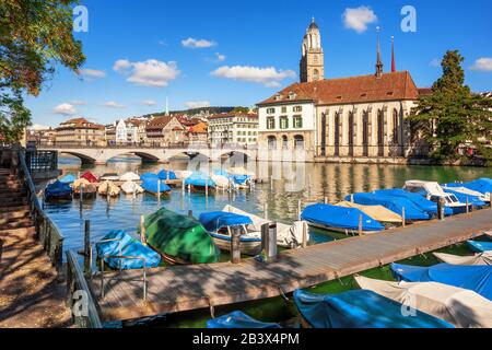 Zürich, Schweiz, historische Innenstadt mit Großmunster Dom, Wasserkkirche und Boote am Limmatfluss Stockfoto