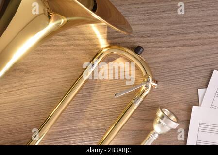 Posaune mit goldenem Objektträger zerlegt und punktet auf Holztisch. Draufsicht. Horizontale Zusammensetzung. Stockfoto